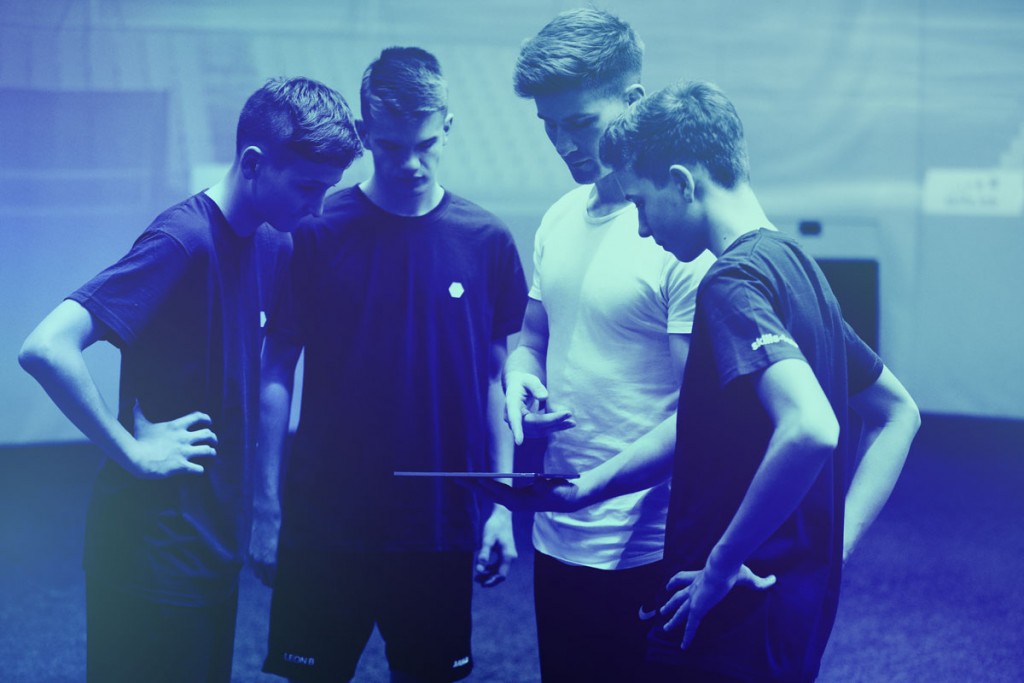 Three youth players getting feedback from a skills.lab coach during a free trial for teenagers